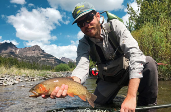 A fly fishing guide proudly shows a trout he just caught near CM Ranch in Dubois, WY | Wyoming dude ranch vacations