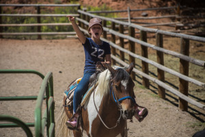 A young girl on a horse raises her arm and shouts at CM Ranch in Dubois, WY | Wyoming dude ranch