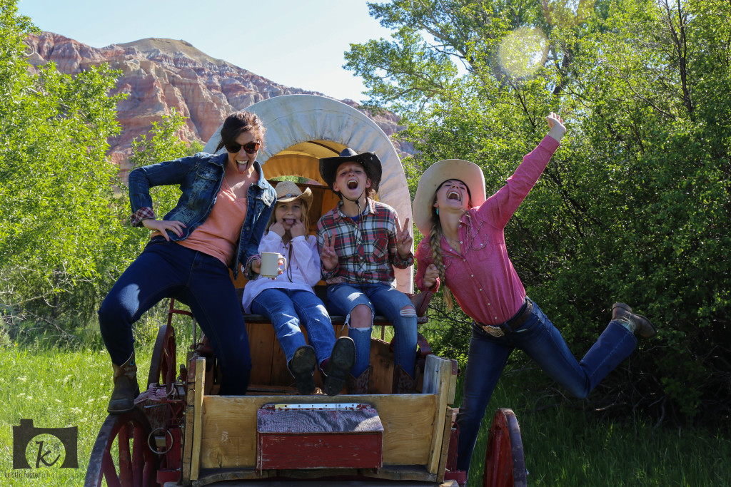 A family shares a light-hearted moment on a covered wagon at CM Ranch in Dubois, WY | Dude Ranch Wyoming Family