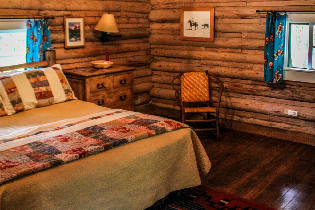 Queen bed, dresser and chair in Dining Cabin 5 | Family Dude Ranch Vacations | CM Ranch