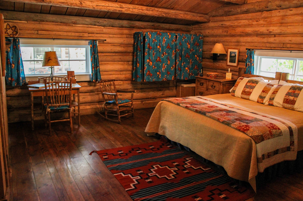 Desk, rocking chair and bed in queen bedroom in Dining Cabin 5 | Family Dude Ranch Vacations | CM Ranch