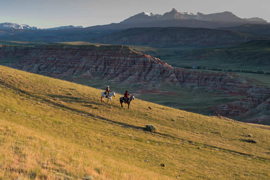 Two riders on horseback in an expansive landscape at sunset at CM Ranch in Dubois, WY | cabins in Dubois Wyoming