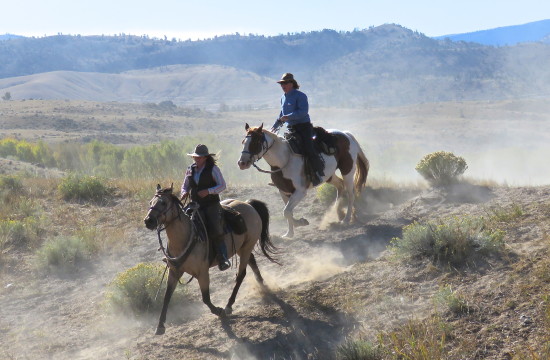 Two riders on horseback on a dusty trail at CM Ranch in Dubois, WY | Wyoming dude ranch